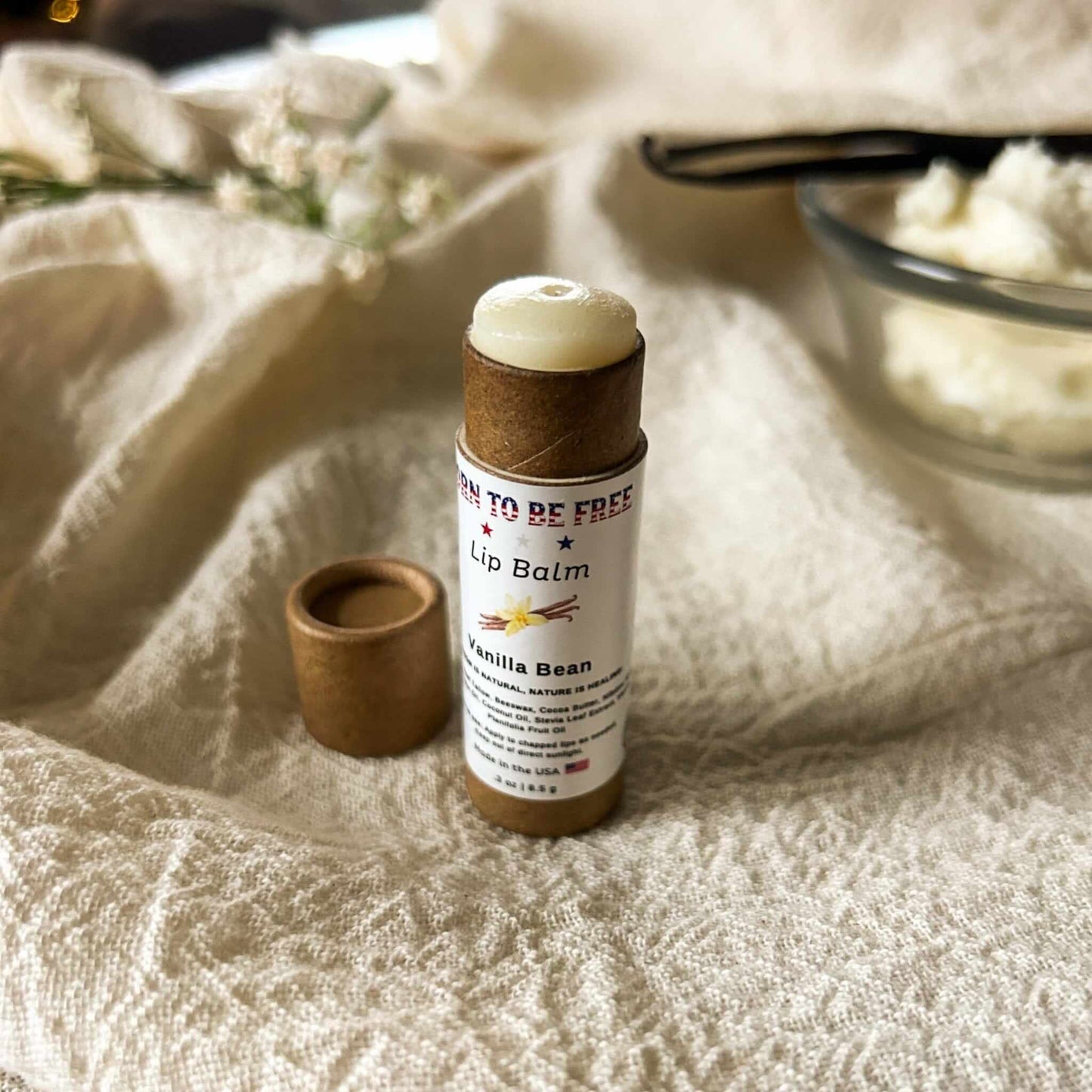 Vanilla Bean Lip Balm tube with cap off, showcasing natural ingredients and smooth texture in a cozy setting.