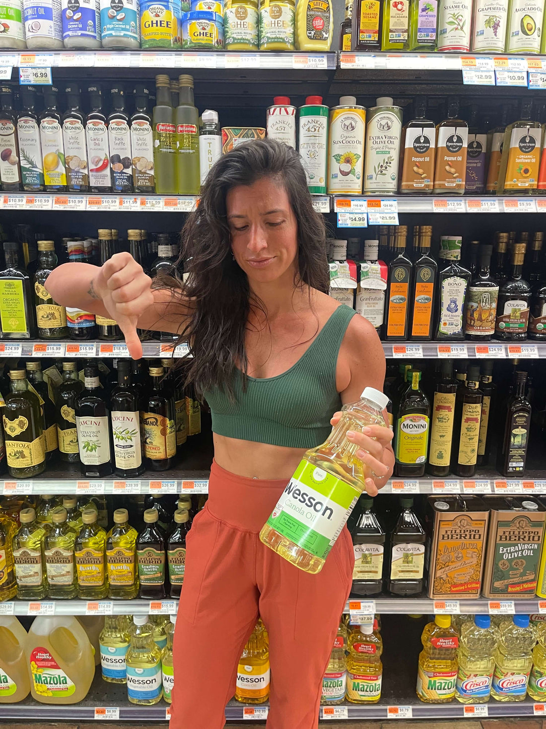 The Truth About Seed Oils- How Bad Are They, woman disapprovingly holding bottle of seed oil in grocery store aisle.