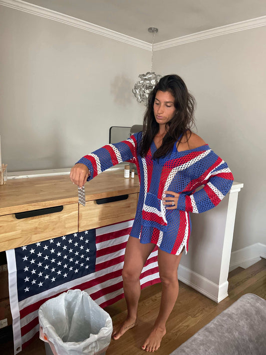 Woman in a red, white, and blue sweater standing by a trash can with an American flag in the background. The Hidden Truth About Hormonal Birth Control