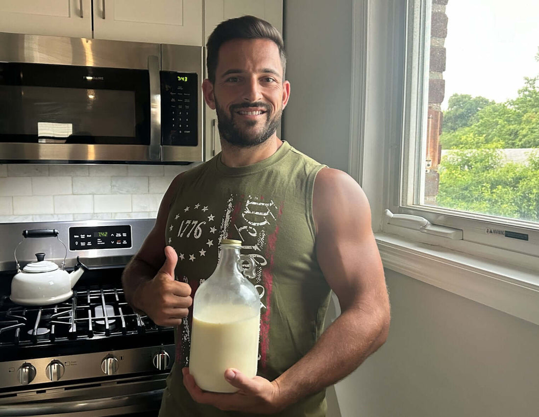Man giving a thumbs up while holding raw milk in a glass bottle, questioning: Is Raw Milk Safe.