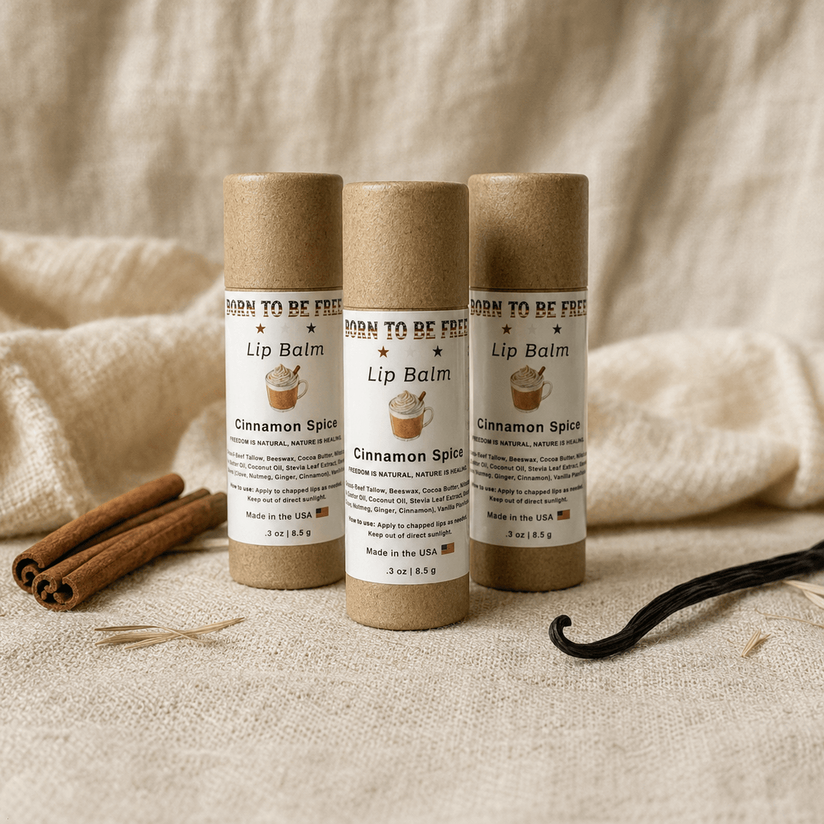Cinnamon Spice Lip Balm tubes stacked on a textured background with cinnamon sticks and vanilla pods.