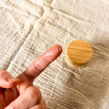 Coconut Vanilla Lip Butter Grapefruit Lemon Lip Butter Lip Butter Set shown on a finger with a wooden container of Vanilla Bean Lip Butter in the background, highlighting deep nourishment for lips from Sweet Peppermint Lip Butter and Sweet Almond Lip Butter