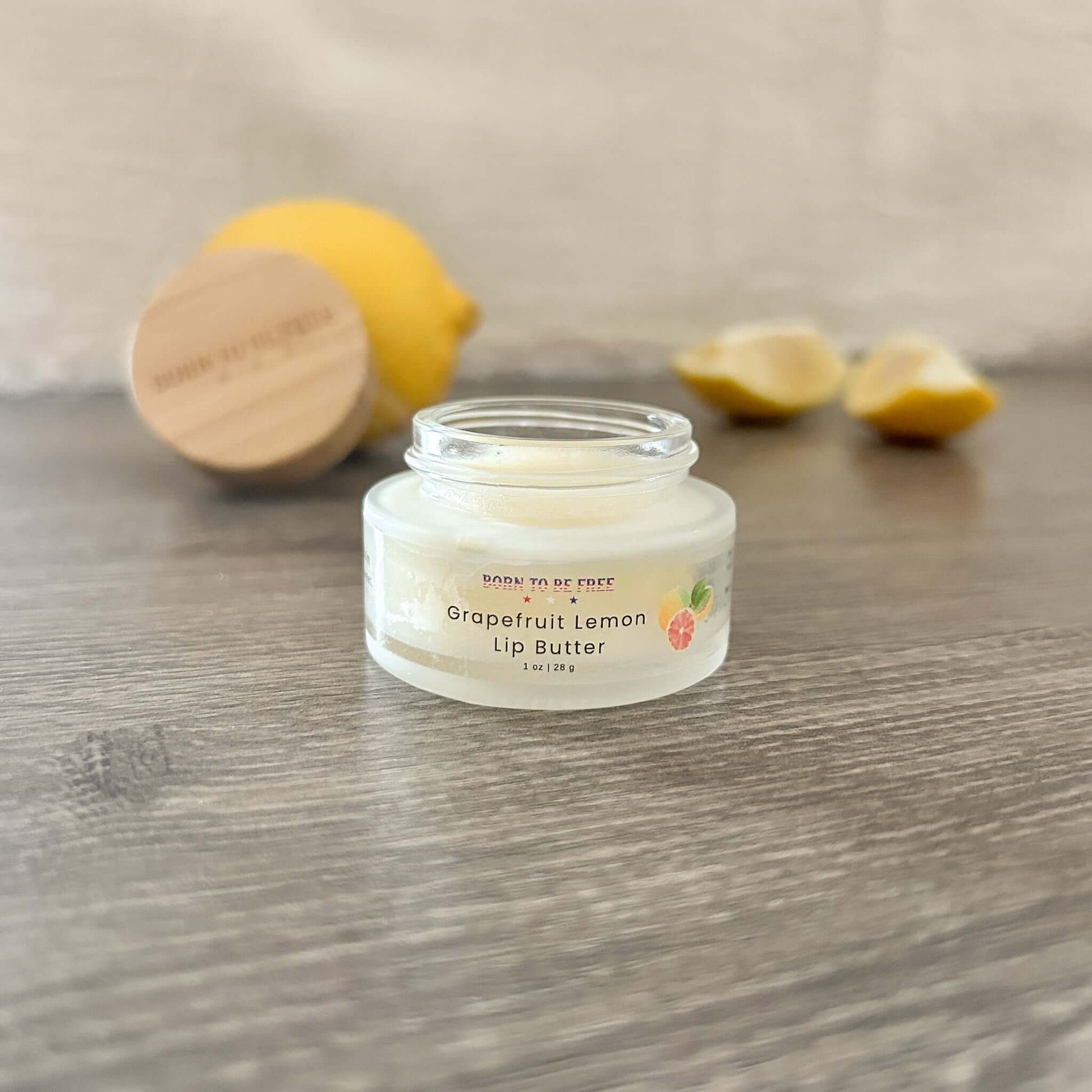 Grapefruit Lemon Lip Butter in a clear jar with lemon slices in the background for hydration and nourishment.