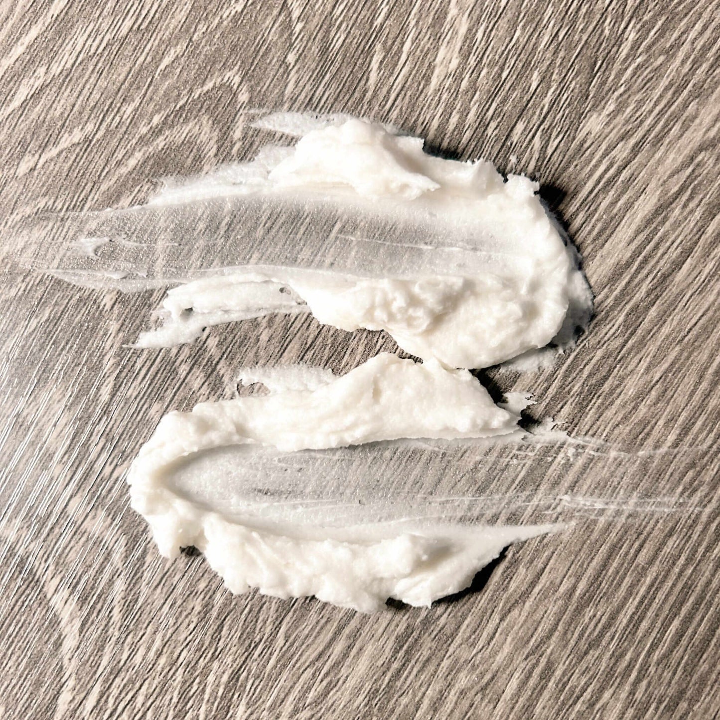 Hydrating Face Butter without Essential Oils applied on a wooden surface, showcasing its creamy texture.