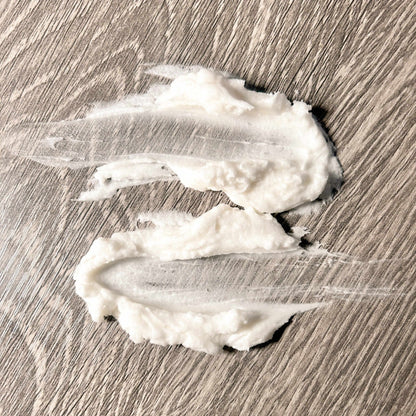 Hydrating Face Butter without Essential Oils applied on a wooden surface, showcasing its creamy texture.