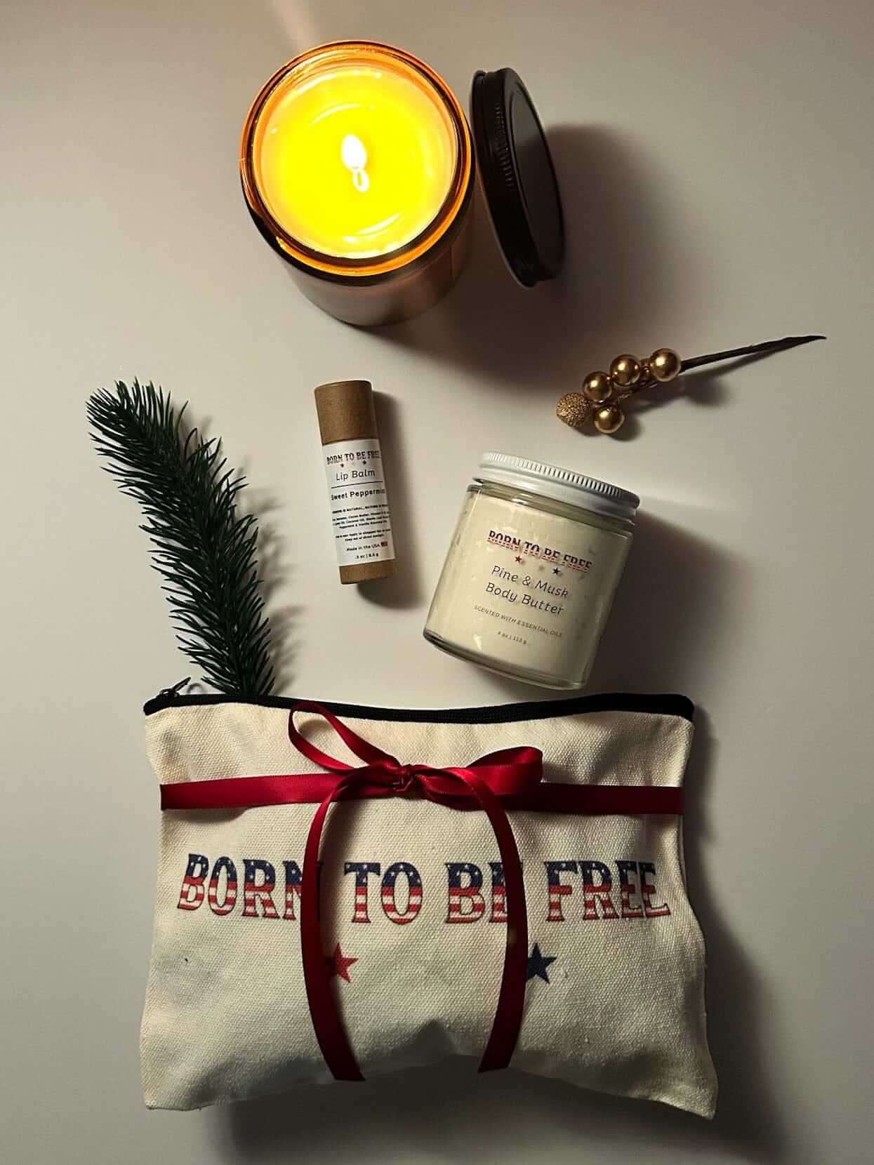 Pine and Mint Holiday Gift Set featuring tallow body butter, peppermint lip balm, and Frosted Pines candle arranged with winter greenery.