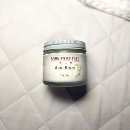 Bum Balm - Baby Diaper Cream with Tallow + Zinc in a 2 oz jar on a soft quilted background.