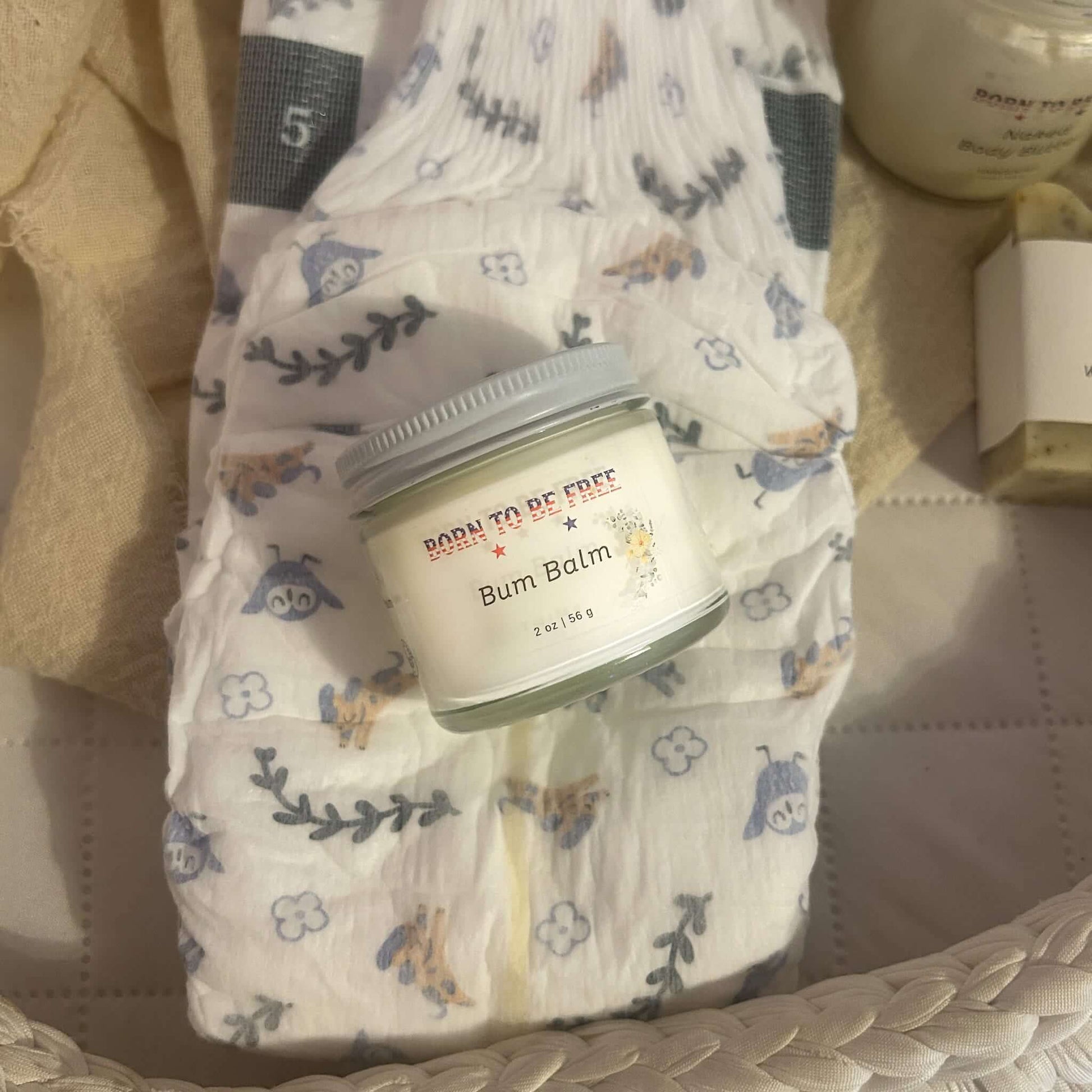 Bum Balm - Baby Diaper Cream with Tallow + Zinc on a changing pad beside diapers.