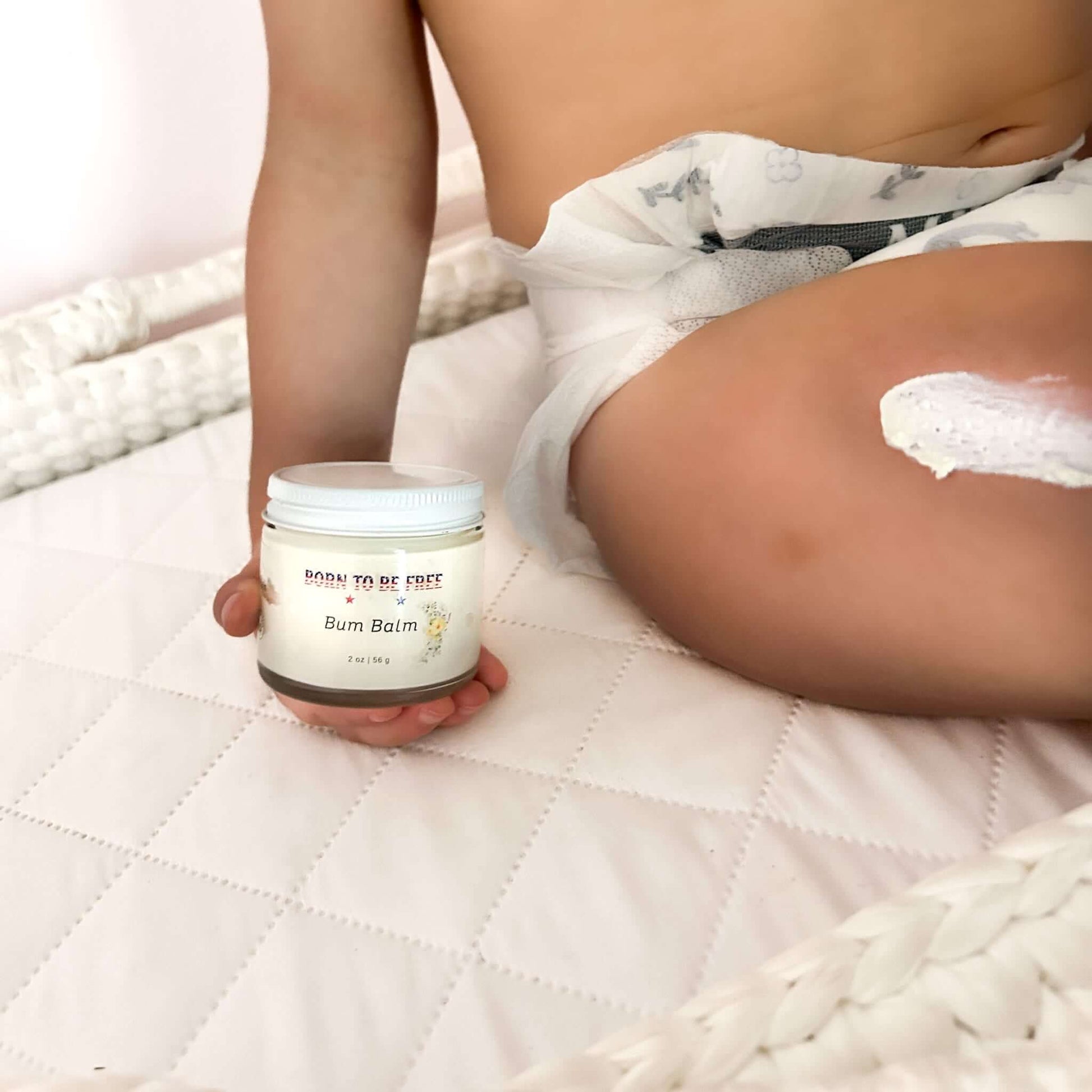 Bum Balm - Baby Diaper Cream with Tallow + Zinc jar beside a baby's leg with cream applied.