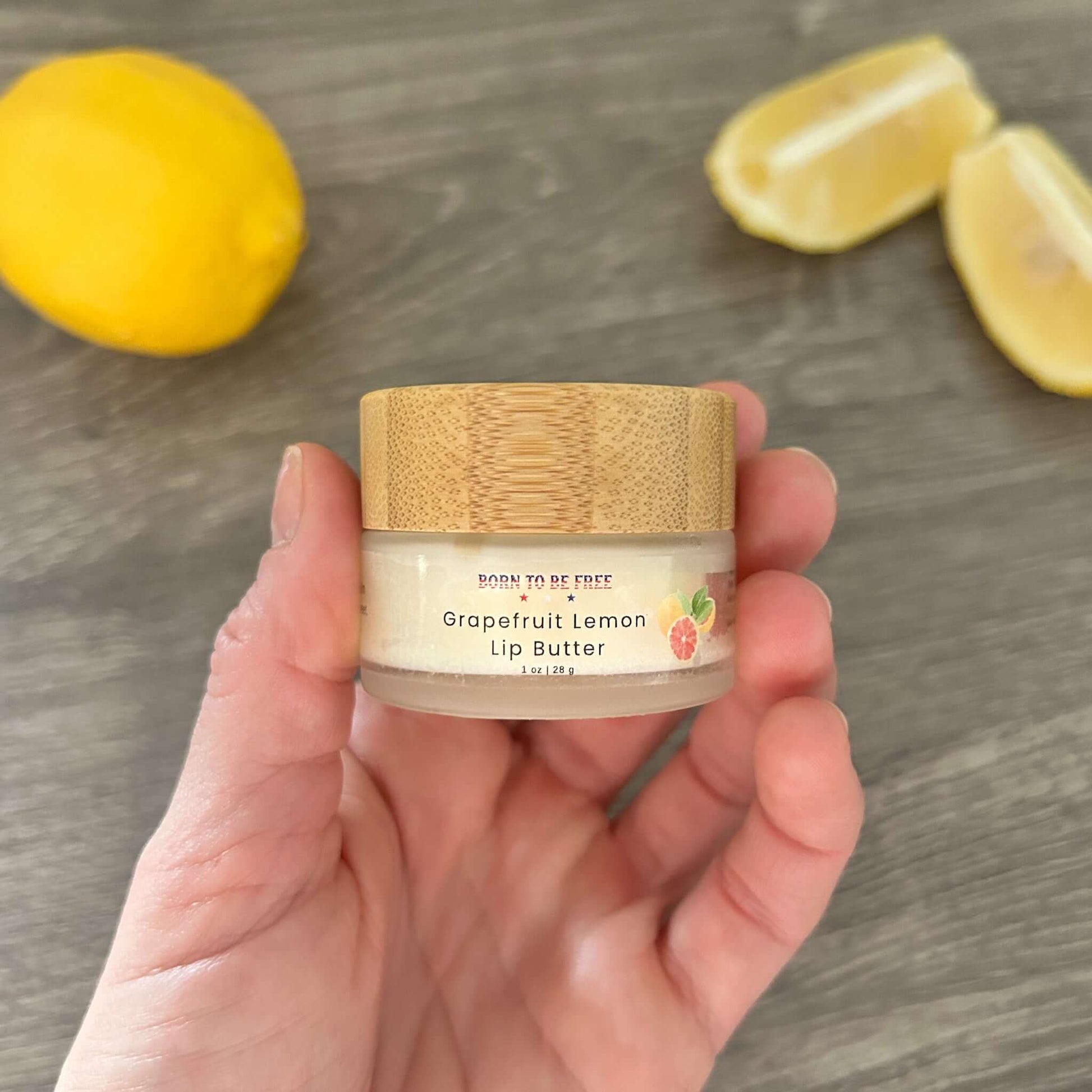 Grapefruit Lemon Tallow Lip Butter in a jar held in hand with lemon and grapefruit slices in the background.