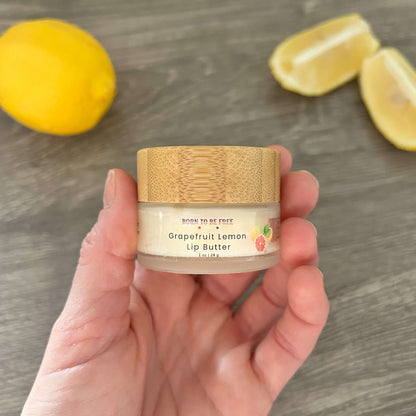 Grapefruit Lemon Tallow Lip Butter in a jar held in hand with lemon and grapefruit slices in the background.