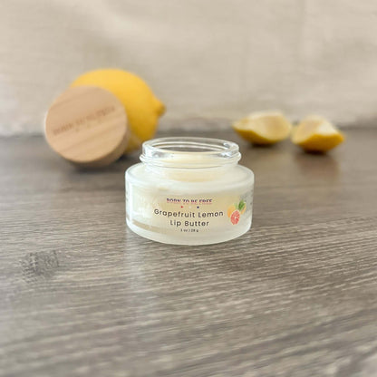 Grapefruit Lemon Tallow Lip Butter in a clear jar with lemon slices in the background for hydration and nourishment.