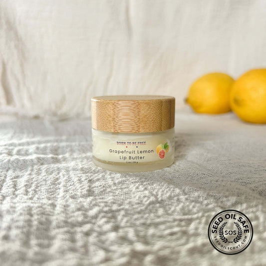 Grapefruit Lemon Tallow Lip Butter in a jar with a bamboo lid, surrounded by fresh lemons, for hydration and nourishment.
