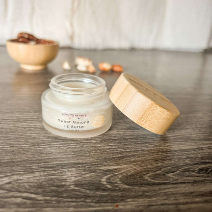 Sweet Almond Tallow Lip Butter in a glass jar with a bamboo lid on a wooden table