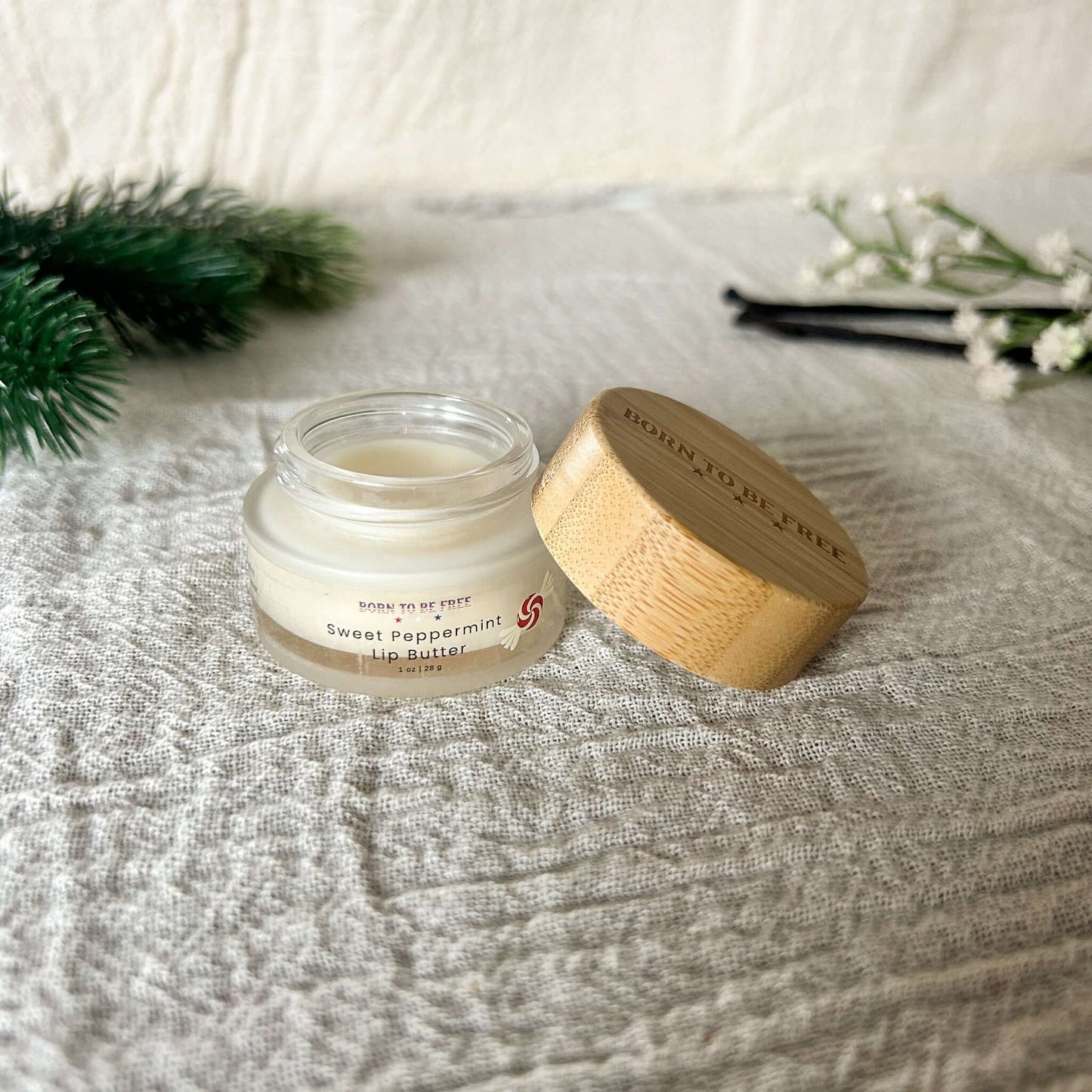 Sweet Peppermint Tallow Lip Butter in a glass container with a bamboo lid, showcasing a luxurious lip treatment.