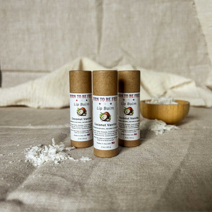 Coconut Vanilla Lip Balm tubes displayed on a textured background with coconut flakes.