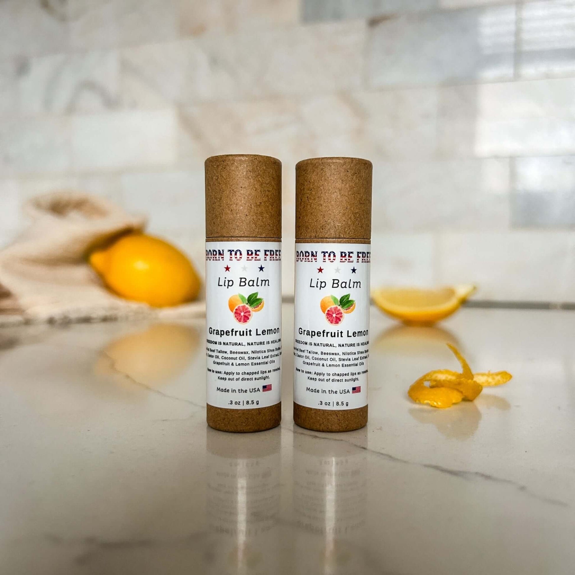 Grapefruit Lemon Lip Balm tubes on countertop with citrus décor, showcasing hydrating natural lip care.