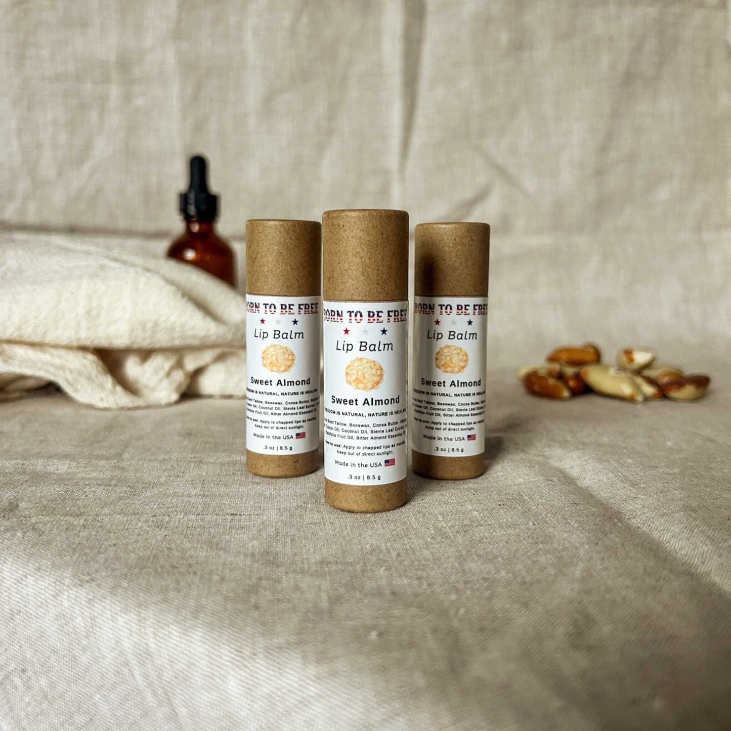 Sweet Almond Lip Balm in eco-friendly packaging on a natural fabric background.