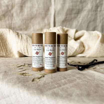 Three tubes of Sweet Peppermint Lip Balm on a soft fabric background, showcasing natural skincare.