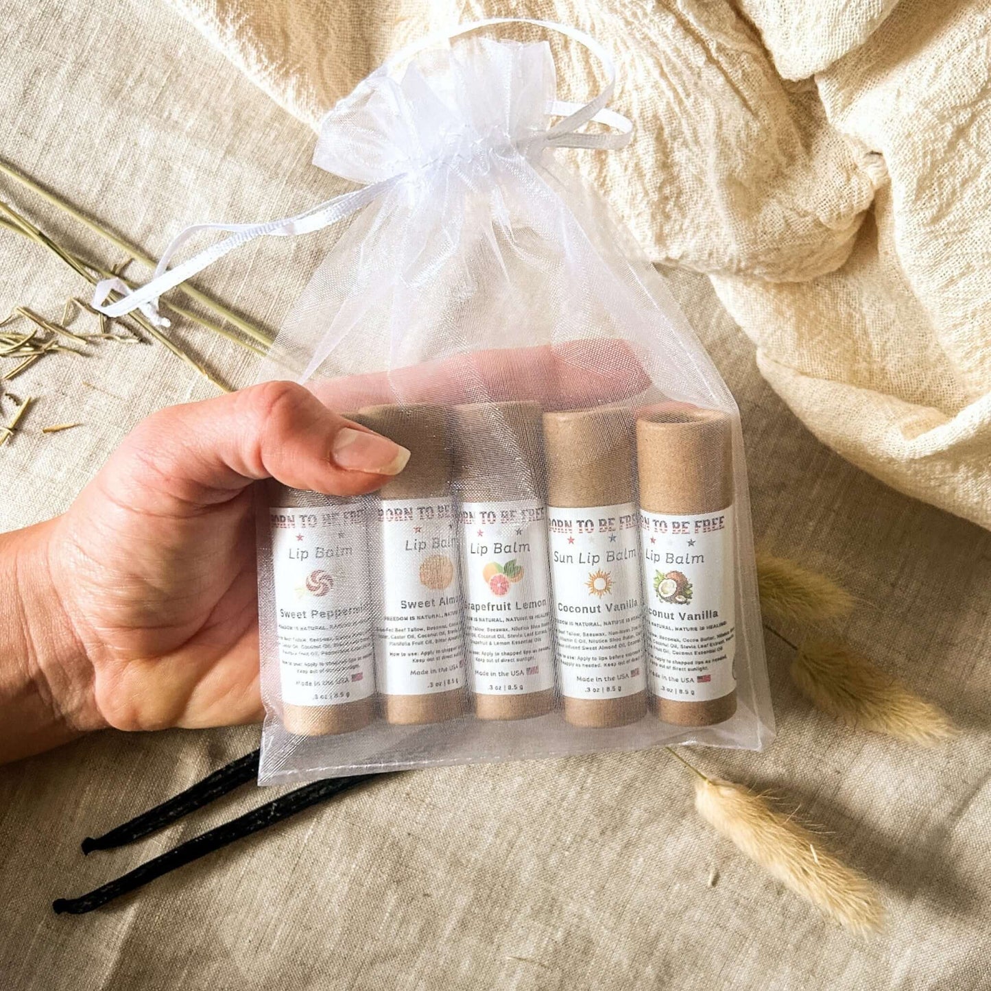 The Balm Bundle - hand holding a pouch of natural lip balms in various flavors.